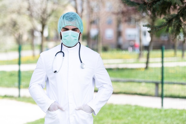Portret van een vermoeide, uitgeputte mannelijke blanke arts voor een park - Coronavirus Covid-19 Virusziekte - Wereldwijde pandemische uitbraak