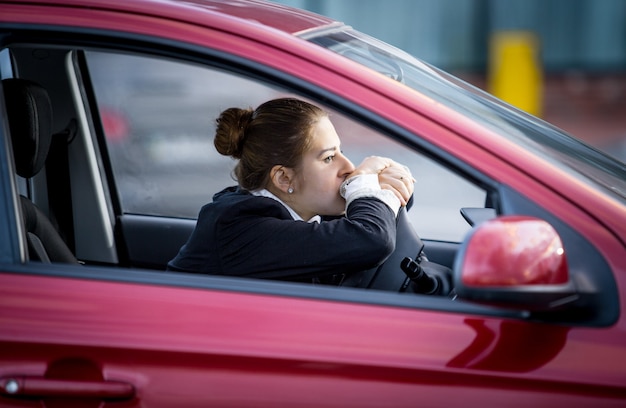 Portret van een vermoeide vrouw die auto rijdt en door het raam kijkt