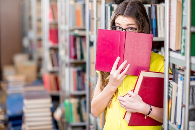 Portret van een vermoeide vrouwelijke student die met boeken studeert in de bibliotheek