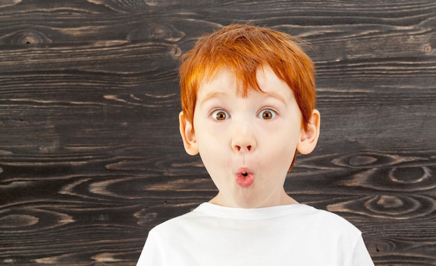 Portret van een verrast kind met rood haar, sproeten en bruine ogen, tegen een zwarte achtergrond