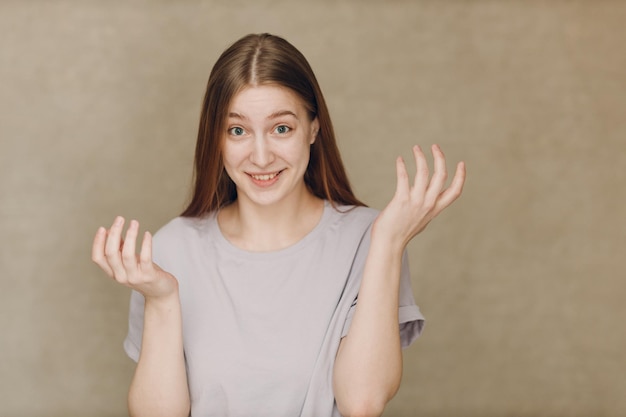 Portret van een verraste jonge blanke vrouw die naar de camera kijkt tegen een beige achtergrond