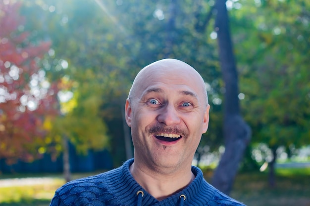 Portret van een verraste kale man in een blauwe trui