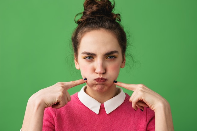 Portret van een verstoorde jonge vrouw die zich geïsoleerd over groen bevindt