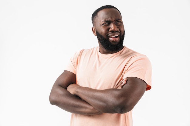 Portret van een verwarde Afrikaanse man met een t-shirt dat geïsoleerd over een witte muur staat, grimassen