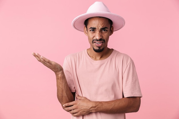 Portret van een verwarde Afro-Amerikaanse man met een hoed met copyspace geïsoleerd op roze