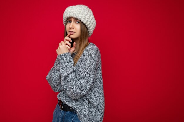 Portret van een volwassen aardige, schattige donkerblonde vrouw met oprechte emoties die een grijze trui en beige draagt