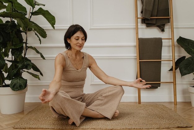 Portret van een volwassen blanke vrouw die haar ogen sluit terwijl ze yoga doet, mediteert en in vlinder pose zit Goedemorgen concept