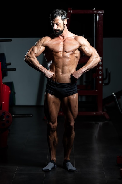 Portret van een volwassen fysiek fitte man die zijn goed getrainde lichaam toont - gespierde atletische bodybuilder fitness model poseren na oefeningen