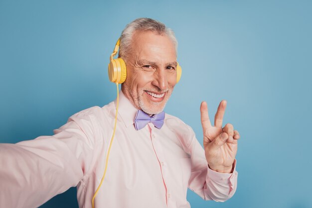 Portret van een volwassen macho die een selfie-hoofdtelefoon neemt met een v-tekensymbool