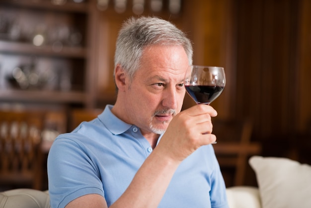 Portret van een volwassen man genieten van een glas rode wijn thuis