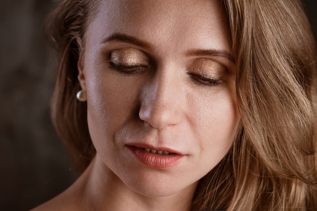 Portret van een volwassen vrouw close-up schone huid op een donkere achtergrond mooie ogen