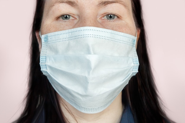 Portret van een volwassen vrouw die een medisch gezichtsmasker draagt dat beschermt tegen luchtwegaandoeningen die worden overgedragen door druppeltjes in de lucht, zoals coronavirus en griep.