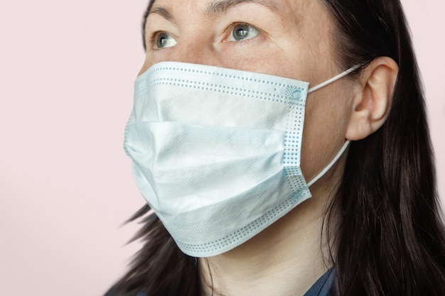 Portret van een volwassen vrouw die een medisch gezichtsmasker draagt dat beschermt tegen luchtwegaandoeningen die worden overgedragen door druppeltjes in de lucht, zoals coronavirus en griep.