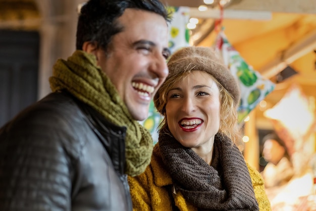 Portret van een volwassen vrouw en een man die buiten lacht op de kerstmarkt.