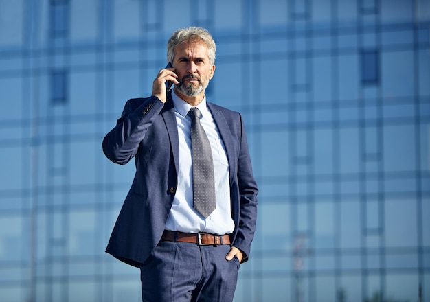 Portret van een volwassen zakenman die buiten aan de telefoon luistert