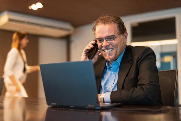 Portret van een volwassen zakenman die een laptopcomputer gebruikt in een horizontaal schot op kantoor