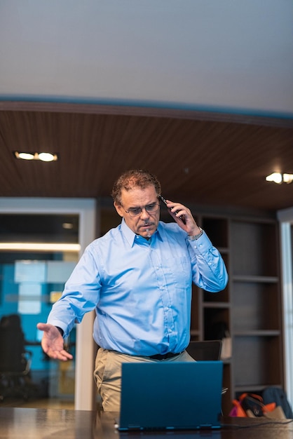 Portret van een volwassen zakenman die werkt en boos kijkt terwijl hij aan de telefoon praat