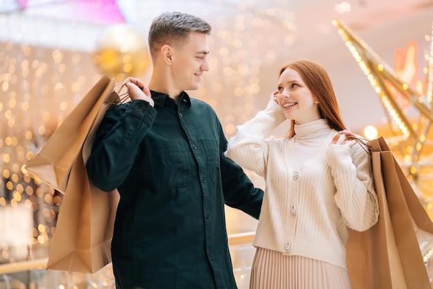 Portret van een vrij mooi jong verliefd stel met boodschappentassen die in het winkelcentrum staan en naar elkaar kijken