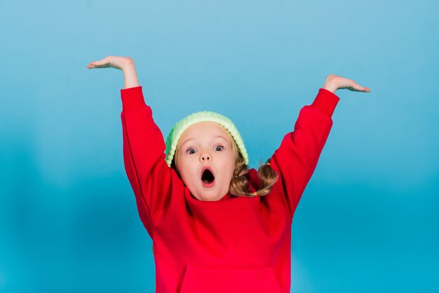 Portret van een vrolijk meisje dat springt en danst tegen de achtergrond van een studio