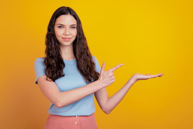 Portret van een vrolijk opgewonden meisje wijst wijsvinger lege ruimte productaanbieding selecteer geïsoleerd over glans kleur achtergrond