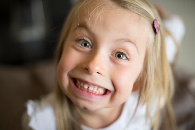 Portret van een vrolijk schattig meisje dat thuis een gezicht maakt