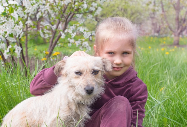 Portret van een vrolijk speels meisje dat haar hond buitenshuis knuffelt