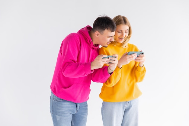 Portret van een vrolijk stel man en vrouw die samen staan tijdens het spelen van videogames op smartphones