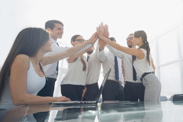 Portret van een vrolijk zakenteam dat de handen ineen slaat in een heldere officephoto met kopieerruimte