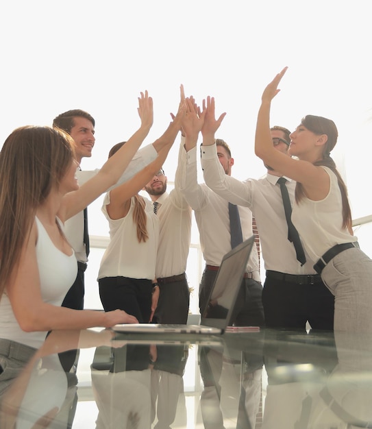 Portret van een vrolijk zakenteam dat de handen ineen slaat in een heldere officephoto met kopieerruimte