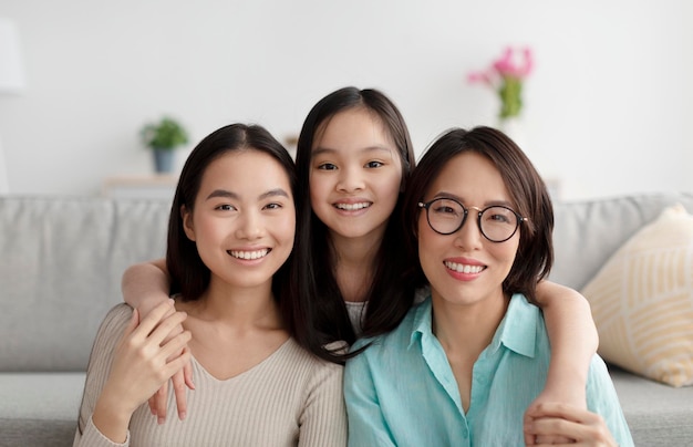 Portret van een vrolijke Aziatische familie van volwassen moeder, volwassen dochter en kleine kleindochter die lacht om