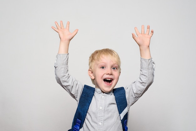 Portret van een vrolijke blonde schooljongen met een schooltas