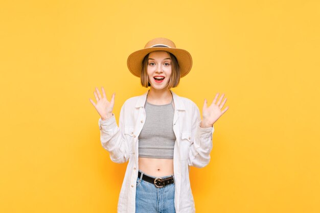 Portret van een vrolijke dame in lichte zomerkleren op gele achtergrond kijkt in de camera