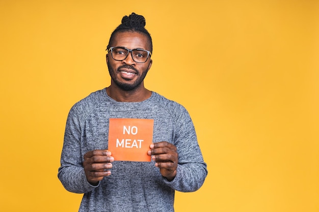 Portret van een vrolijke gelukkig lachende jonge Afro-Amerikaanse zwarte man staande geïsoleerd over gele achtergrond. Veganistisch, vegetarisch concept.