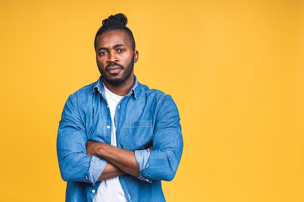 Portret van een vrolijke gelukkig lachende jonge Afro-Amerikaanse zwarte man staande geïsoleerd over gele achtergrond.