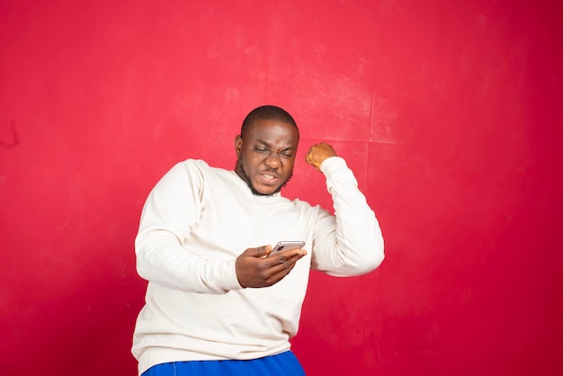 Portret van een vrolijke jonge man met een mobiele telefoon
