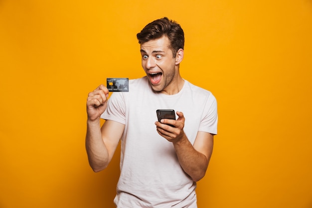 Portret van een vrolijke jonge man met mobiele telefoon