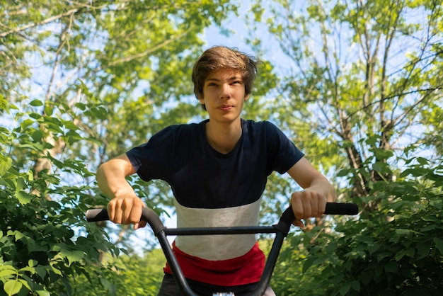 Foto portret van een vrolijke jonge man op de fiets, rijdend in de straten van de stad