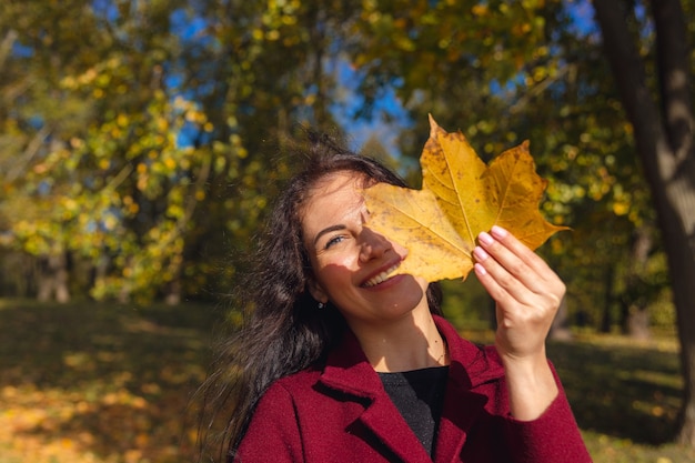 Portret van een vrolijke jonge vrouw die geniet in het herfstpark.