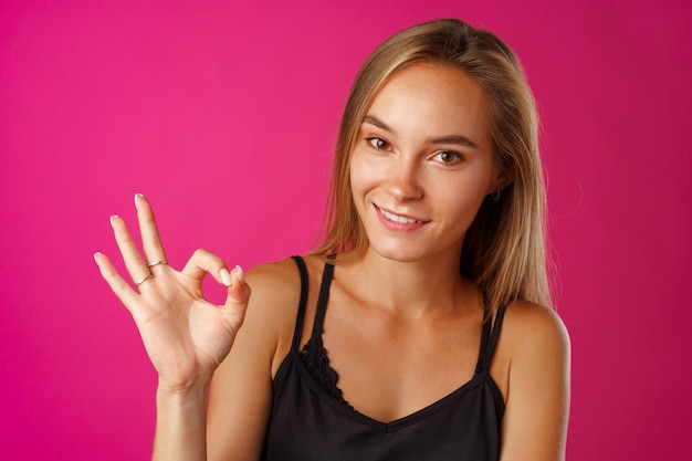 Foto portret van een vrolijke jonge vrouw die ok teken toont