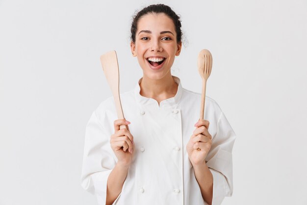 Portret van een vrolijke jonge vrouw met keukengerei