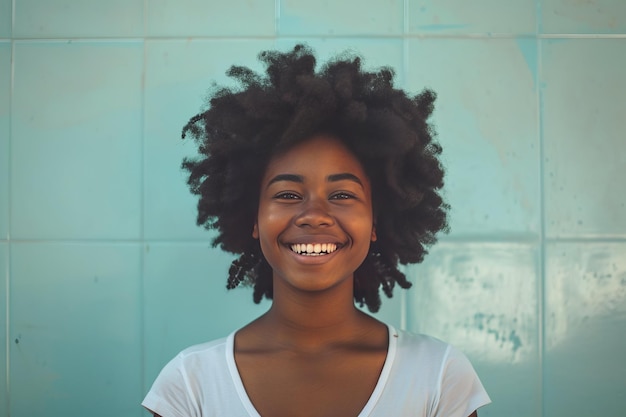 Portret van een vrolijke jonge vrouw met krullend haar die glimlacht tegen een turquoise achtergrond