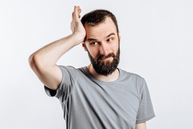 Portret van een vrolijke jongeman die lacht terwijl hij naar de camera kijkt en zijn handen naar de zijkanten uitsteekt op een wit oppervlak