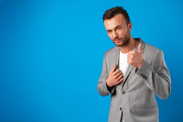 Portret van een vrolijke man die lacht en duim toont over blauwe achtergrond