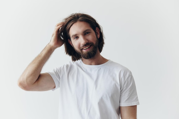 Portret van een vrolijke man met een zwarte dikke baard en lang haar met een vriendelijke glimlach in een wit T-shirt op een witte geïsoleerde achtergrond