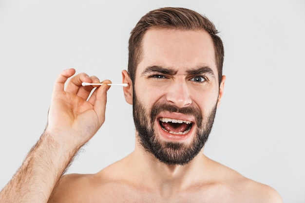 Portret van een vrolijke shirtless bebaarde man geïsoleerd over wit, met wattenstaafje