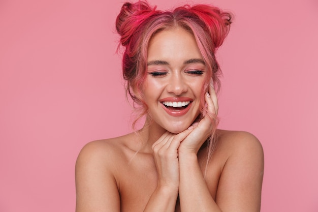 Portret van een vrolijke shirtloze jonge vrouw met kleurrijk kapsel en make-up die lacht met gesloten ogen