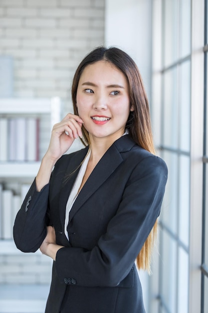 Portret van een vrolijke volwassen Aziatische zakenvrouw bij In de kantoorruimte achtergrondbedrijf sprak vertrouwen uit, aanmoedigend en succesvol concept