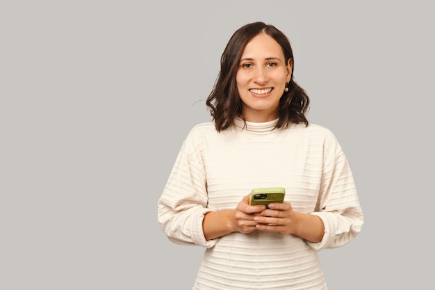 Portret van een vrolijke vrouw houdt telefoon vast en kijkt naar de camera