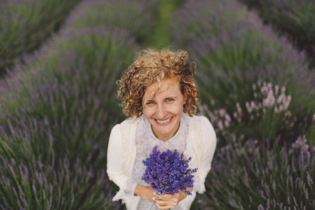 Portret van een vrolijke vrouw met lavendelbloemen op het veld