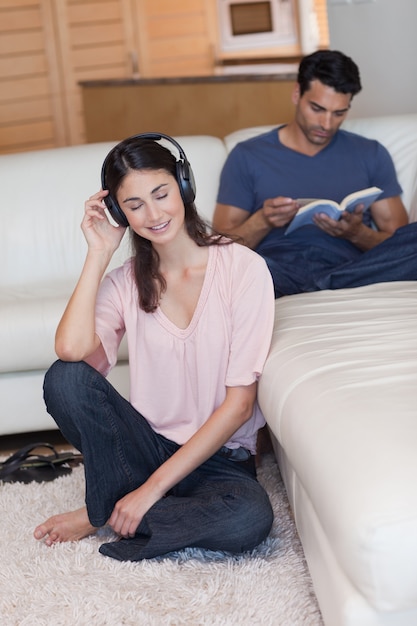 Portret van een vrouw die aan muziek luistert terwijl haar fiance een boek leest